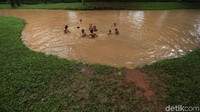 Ari kolam berwarna kecoklatan ini tidak menyurutkan niat anak-anak ini untuk berenang.