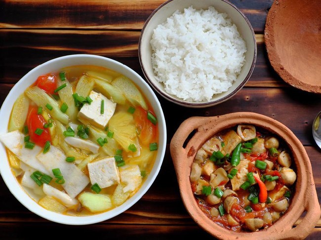 Top view vegetarian meal, vegetables soup from ingredient food as tomato, pineapple, bamboo shoot and tofu, mushroom cook with soy sauce, simple dish for vegan diet on wooden background