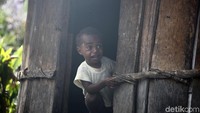 Seorang anak tengah beraktivitas di rumah adat Honai.