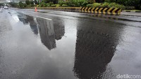 Refleksi gedung-gedung bertingkat di genangan air.