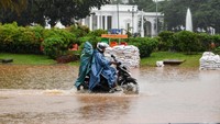Pengendara sepeda motor melintasi banjir di Jalan Medan Merdeka Barat, Jakarta, Minggu (2/2/2020).