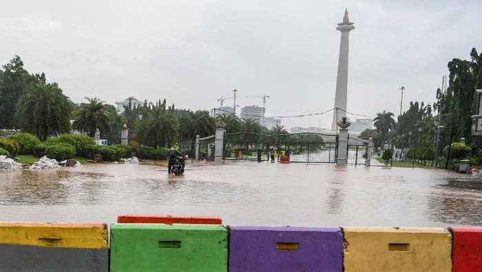 Warga mendorong motor melintasi banjir di kawasan Monas, Jalan Medan Merdeka Barat, Jakarta, Minggu (2/2/2020). Hujan deras yang mengguyur Jakarta pada Minggu (2/2) pagi menyebabkan beberapa ruas jalan di ibu kota tergenang banjir dengan ketinggian 10-50 centimeter. ANTARA FOTO/Hafidz Mubarak A/aww.