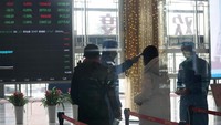Pekerja yang mengenakan pakaian pelindung mengukur suhu pengunjung di lobi gedung Shanghai Stock Exchange di Shanghai, Senin, 3 Februari 2020. Kekhawatiran akan menyebarnya virus Corona masih tinggi. Seluruh dunia sekarang siaga demi menahan masuknya virus yang belum ada obatnya itu. Foto: AP Photo