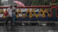 Dua orang warga menerobos hujan dan angin kencang.