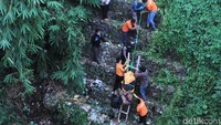 Jasad yang telah dimasukkan ke kantong mayat lalu diikat di tangga kayu dan ditarik oleh puluhan orang.