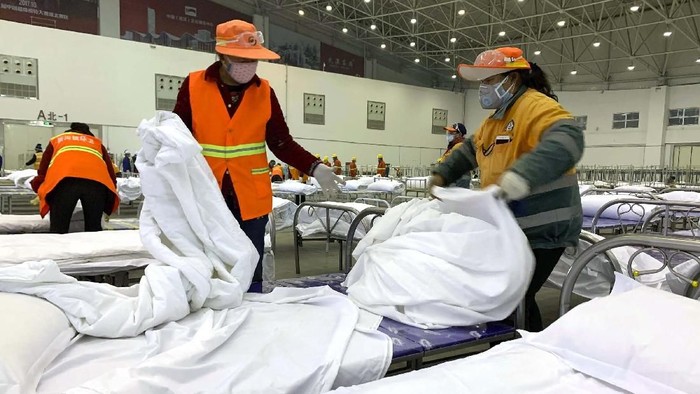 Workers arrange beds in a convention center that has been converted into a temporary hospital in Wuhan in central Chinas Hubei Province, Tuesday, Feb. 4, 2020. China said Tuesday the number of infections from a new virus surpassed 20,000 as medical workers and patients arrived at a new hospital and President Xi Jinping said we have launched a peoples war of prevention of the epidemic. (Chinatopix via AP)