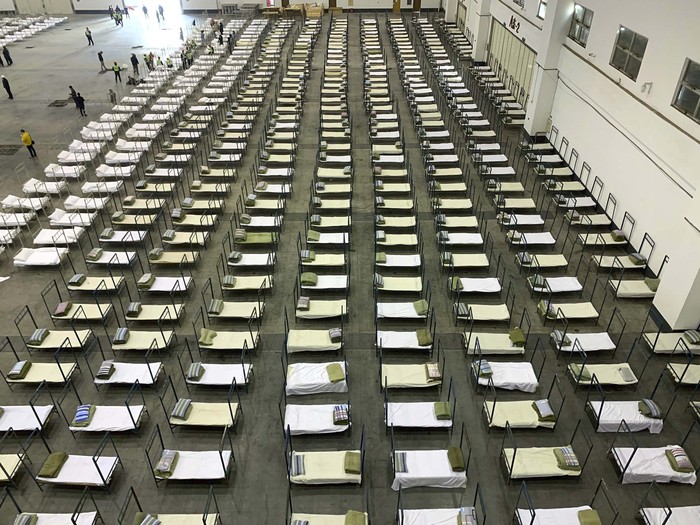 Workers arrange beds in a convention center that has been converted into a temporary hospital in Wuhan in central China's Hubei Province, Tuesday, Feb. 4, 2020. China said Tuesday the number of infections from a new virus surpassed 20,000 as medical workers and patients arrived at a new hospital and President Xi Jinping said 