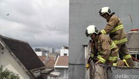 Petugas naik ke rumah tetangga korban untuk memadamkan api.