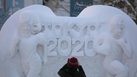 Seorang wanita memotret patung salju yang mempromosikan Tokyo 2020.