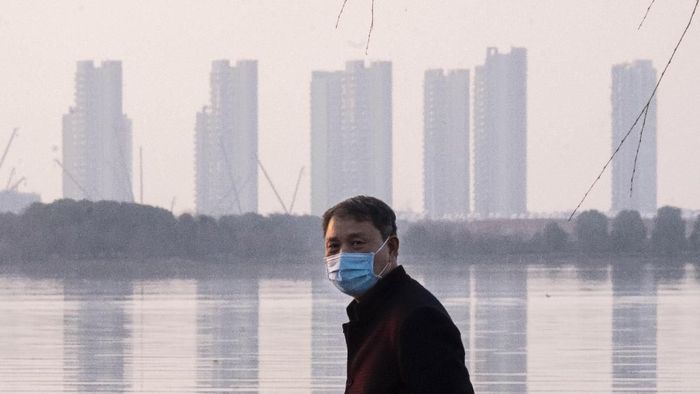 Seorang warga Wuhan memakai masker di tengah wabah virus corona dalam foto tanggal 30 Januari FILE - In this Jan. 30, 2020 file photo, a man wears a face mask as he stands along the waterfront in Wuhan in central Chinas Hubei Province. Arek and Jenina Rataj were starting a new life in the Chinese industrial center of Wuhan when a viral outbreak spread across the city of 11 million. While they were relatively safe sheltering at home, Arek felt compelled to go out and document the outbreak of the new type of coronavirus. Among his subjects: the construction of a new hospital built in a handful of days; biosecurity check points; and empty streets. (AP Photo/Arek Rataj, File)