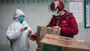 Seorang kurir mengirimkan pasokan logistik ke Wuhan Union Hospital di Provinsi Hubei, Wuhan, China. Karena jalur transit ditutup dan kurangnya persediaan logistik, kurir menjadi andalan untuk memasok logistik kota tersebut. Foto: Getty Images