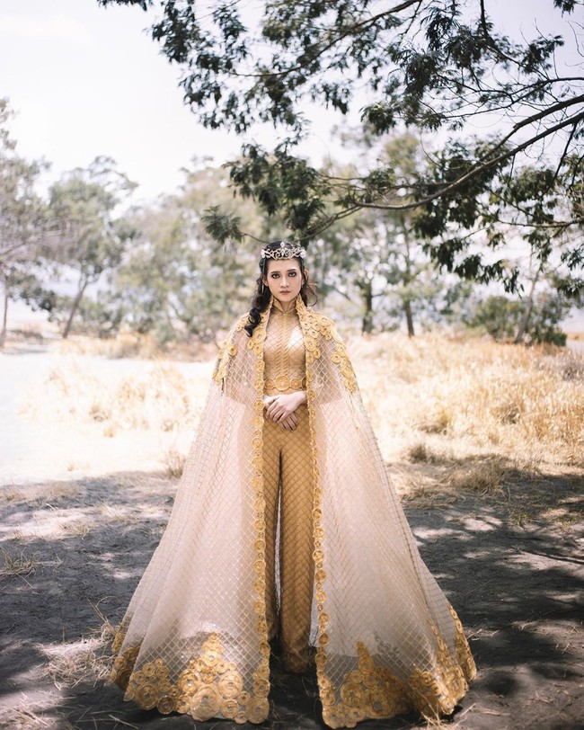 Masih dalam tema Timur Tengah,  busana bernuansa emas tersebut terdiri dari jumpsuit brokat yang dilengkapi cape dramatis. Tidak ketinggalan, sebuah headpiece bergaya mahkota sebagai sentuhan akhir. (Foto: Instagram/@berlianinsyirah)