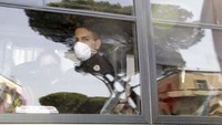 Seorang warga Italia memakai masker saat dia bersama warga lainnya dibawa ke panggalan militer Italia, Senin, 3 Februari 2020.