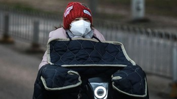 Seorang wanita mengendarai sepeda dengan perlengkapan pelindung virus. Foto: Getty Images