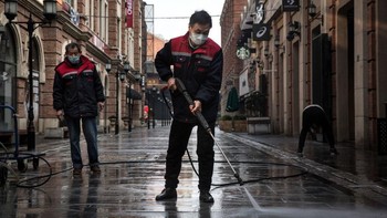 Petugas kebersihan membersihkan jalan dengan semprotan air bertekanan tinggi. Foto: Getty Images