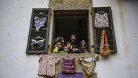 Para warga yang tidak ikut parade akan melihat tradisi ini dari jendela rumah. Sambil mendokumentasikannya, warga menikmati karnaval kuno ini. (AP Photo/Alvaro Barrientos)