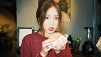 Memakai sweater merah yang hangat, ini momen Lee Sung Kyung saat menyantap burger untuk makan malamnya. Foto: Instagram @heybiblee