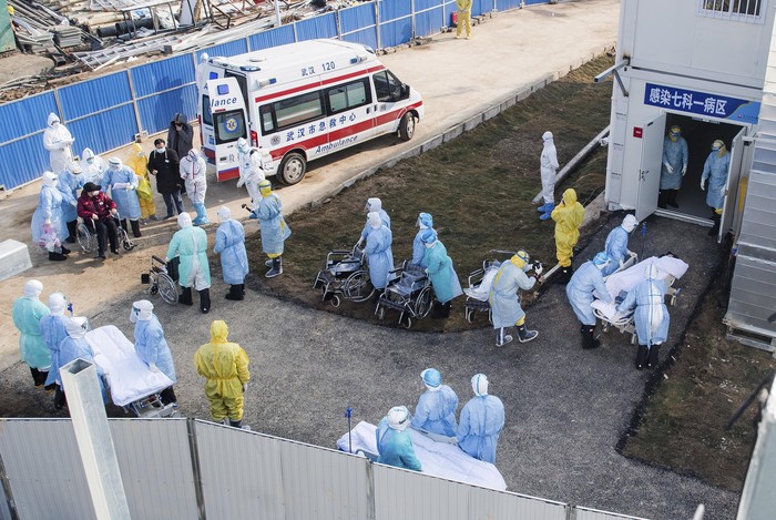 In this photo released by Chinas Xinhua News Agency, medical workers in protective suits help transfer the first group of patients into the newly-completed Huoshenshan temporary field hospital in Wuhan in central Chinas Hubei province. China said Tuesday the number of infections from a new virus surpassed 20,000 as medical workers and patients arrived at a new hospital and President Xi Jinping said 