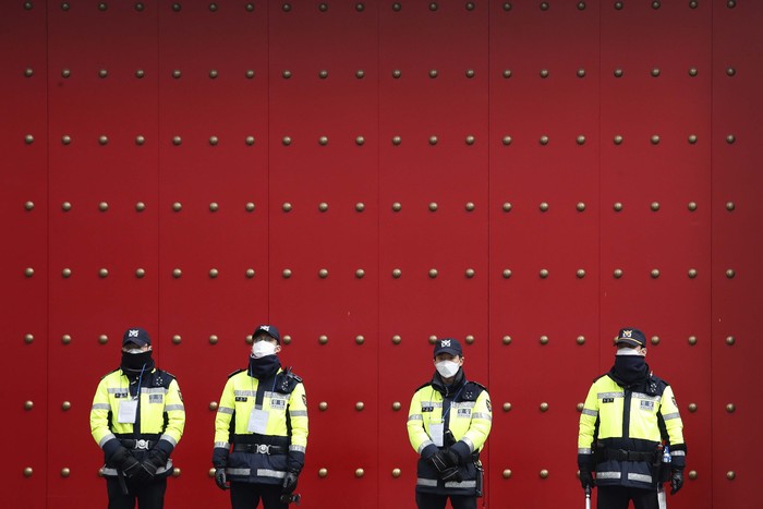 Police officers stand guard as protesters stage a rally calling for a ban on Chinese people entering South Korea in front of the Chinese embassy in Seoul, South Korea, Tuesday, Feb. 4, 2020. The death toll in mainland China from the new type of virus has risen to 425, with the total number of cases now standing at 20,438, officials said Tuesday. (AP Photo/Ahn Young-joon)