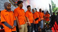Para tersangka sudah mengenakan baju tahanan. Polisi juga mengenakan penutup wajah ke para tersangka.
