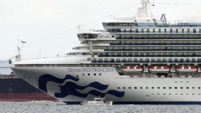 A small boat navigates near a cruise ship Diamond Princess anchoring off the Yokohama Port Tuesday, Feb. 4, 2020, in Yokohama, near Tokyo. Japanese health officials are conducting extensive medical checks on all 3,700 passengers and crew of the cruise ship that returned to the country after one passenger tested positive for the new coronavirus. (AP Photo/Eugene Hoshiko)