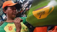Petugas membuat gambar cangkir pada pot yang terbuat dari ban bekas.