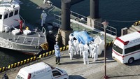 Para pekerja medis yang mengenakan pakaian pelindung membawa penumpang yang positif corona ke rumah sakit. Hiroko Harima/Kyodo News via AP.