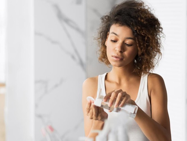 African American Millennial Girl Using Micellar Water And Cotton Pads Refreshing And Cleaning Skin In Bathroom. Panorama