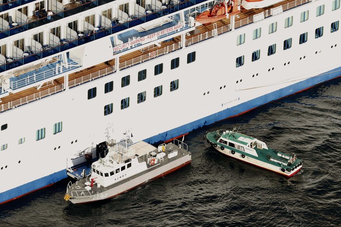 Medical workers in protective suits take a passenger tested positive for a new coronavirus from the cruise ship Diamond Princess to ambulances at Yokohama Port in Yokohama, south of Tokyo, Wednesday, Feb. 5, 2020. Japan said Wednesday 10 people on the cruise ship have tested positive for the new virus and were being taken to hospitals. Health Minister Nobukatsu Kato said all the 3,700 people and passengers on the ship will be quarantined on board for up to 14 days under Japanese law. (Hiroko Harima/Kyodo News via AP)