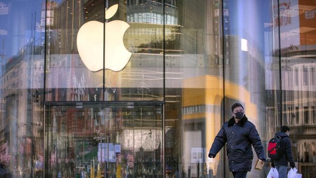 Orang-orang memakai masker dan berjalan melewati toko Apple yang ditutup bersama dengan semua toko Apple lainnya di Cina karena masalah kesehatan di tengah wabah virus. (AP Photo/Mark Schiefelbein)