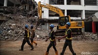 Sejumlah petugas tampak melintas di samping alat berat yang tengah melakukan pembongkaran bangunan Graha Bhakti Budaya dan Galeri Cipta I yang berada di kawasan Taman Ismail Marzuki, Jakarta, Kamis (6/2/2020).