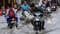 Para pelajar asyik bersenda gurau sambil menaiki motor mereka ditengah genangan banjir.