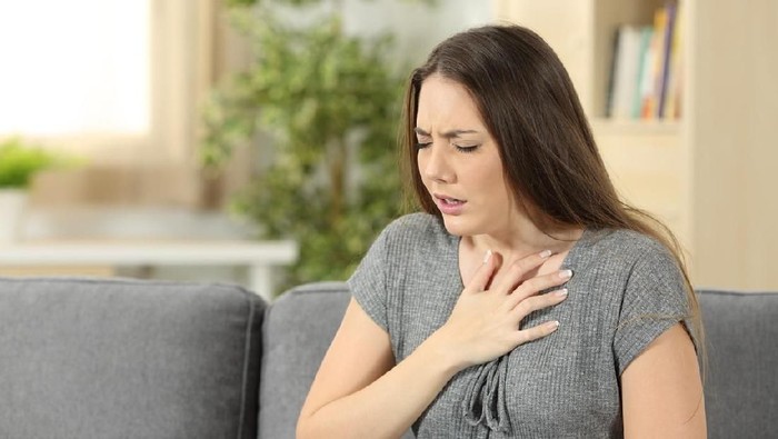 tulang ikan Woman suffering respiration problems sitting on a couch in the living room at home
