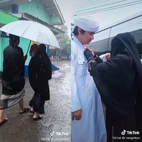 Pada salah satu video yang diunggah Neng Ros terlihat, Nengmas yang menggendong anaknya berjalan kaki sambil berpayungan bersama dengan suaminya menuju kediaman wanita yang akan jadi istri kedua. Hingga tiba saatnya acara akad nikah. Video memperlihatkan Nengmas sendiri yang membawa baju akad nikah suaminya beserta mas kawin yang akan diserahkan ke istri kedua. Dia pun membantu suaminya untuk memakai jubah putih dan kain yang disematkan di pundak sebelah kanan sebelum akad nikah berlangsung. Foto: Dok. TikTok @nengnthan.