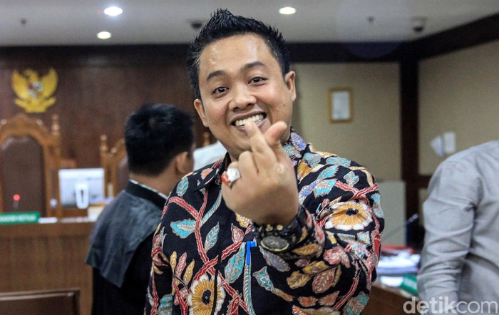 Gaya 'Finger Heart' Sambil Cengengesan ala Eks Aspri Menpora Eks asisten pribadi Menpora Imam Nahrawi, Miftahul Ulum memberikan gestur finger heart saat jalani sidang di Pengadilan Tipikor, Jakarta.