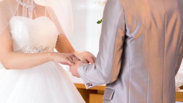 menikah Happy bride and groom exchaning wedding ring in chapel
