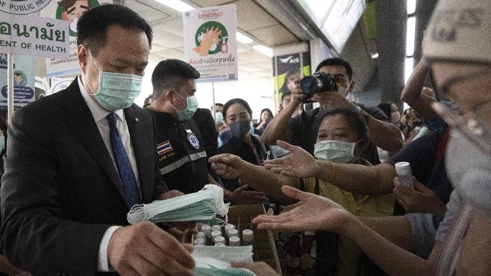 Thailands Public Health Minister Anutin Charnvirakul, left, distributes masks to commuters during a campaign for wearing masks and washing hands at the skytrain station in Bangkok, Thailand, Friday, Feb. 7, 2020. The coronavirus outbreak in China has thrown Thailandâ€™s and other Asian countriesâ€™ travel industry into chaos, threatening billions in losses as millions of would-be travelers are staying home. (AP Photo/Sakchai Lalit)