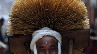 Seorang umat Hindu di Nepal berkeliling sambil mengenakan hiasan jerami di kepala sebagai bagian dari ritual Festival Madhav Narayan.