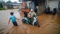 Pengendara mendorong motornya yang mogok akibat menerobos banjir di Perumahan Rajasanagara.