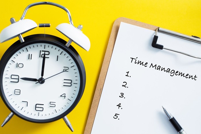 Time management concept. Alarm clock on yellow background.
