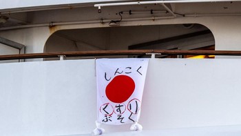 Bendera Jepang dengan pesan bertuliskan kekurangan obat digantung di balkon di atas kapal pesiar Diamond Princess. Dalam proses karantinanya, kapal ini merapat di pelabuhan Daikoku. Foto: Getty Images