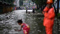 Para pengendara memilih menunggu banjir surut. Sementara anak-anak justru asyik bermain air di jalan tersebut.
