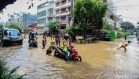 Selain bermain, sejumlah anak juga ikut membantu mendorong motor menerobos banjir.