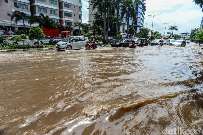 Pengendara melintasi banjir yang menggenangi Jalan Mitra Sunter Boulevard, Jakarta Utara, Sabtu (8/2/2020).   Air surut terpantau sekitar pukul 15.00 WIB.