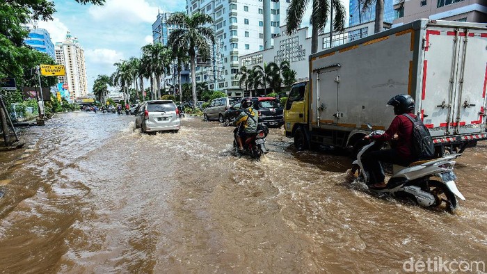 Pengendara melintasi banjir yang menggenangi Jalan Mitra Sunter Boulevard, Jakarta Utara, Sabtu (8/2/2020).   Air surut terpantau sekitar pukul 15.00 WIB.
