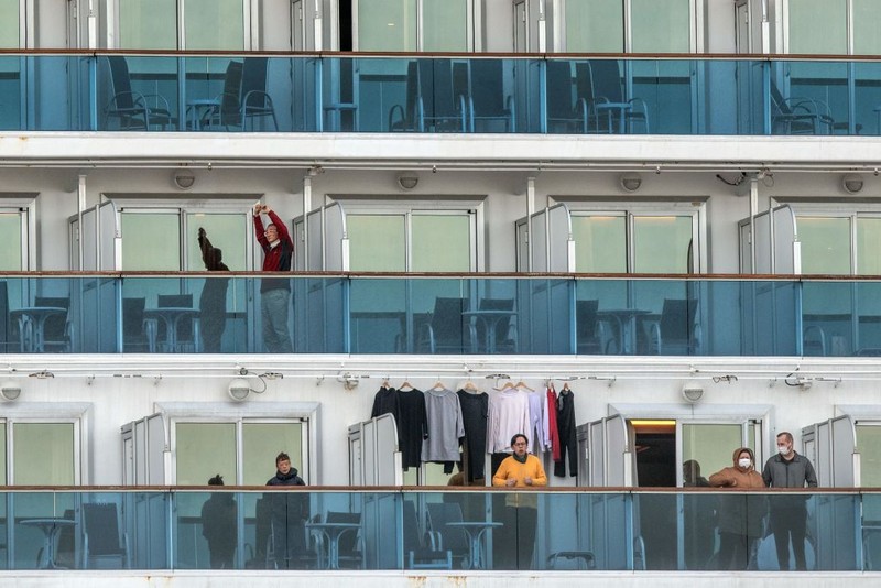 YOKOHAMA, JAPAN - FEBRUARY 07: A passenger jogs on the spot as another stretches as they wait on the balconies of their cabins on the Diamond Princess cruise ship as it sits docked at Daikoku Pier where it is being resupplied and newly diagnosed coronavirus cases taken for treatment as it remains in quarantine after a number of the 3,700 people on board were confirmed to have coronavirus, on February 7, 2020 in Yokohama, Japan. 61 passengers are confirmed to be infected with coronavirus as Japanese authorities continue screening people on board. The new cases bring the total number of confirmed infections to 86 in Japan, the largest number outside of China. (Photo by Carl Court/Getty Images)
