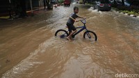 Sejumlah anak juga bermain sepeda di genangan banjir.