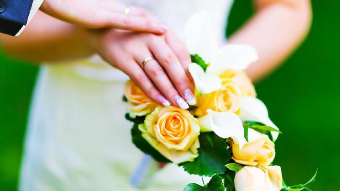 Macro view of the hands of married couple of bride and groom with golden wedding rings with selective focus effect