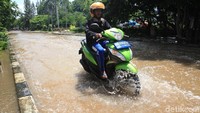 Pengendara sepeda motor nekat menerobos banjir di jalan tersebut. Pengendara sepeda motor nekat menerobos banjir di jalan tersebut.