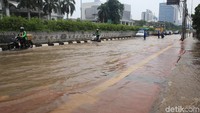 Pengendara sepeda motor menerobos banjir.